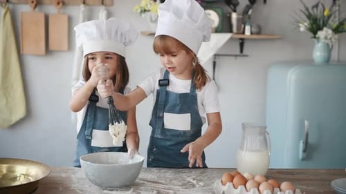 Zwei Kinder in weißer Kochuniform mischen Mehl in einer Schüssel in der Küche