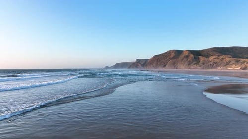 Cliff-lined beach with rolling surf waves