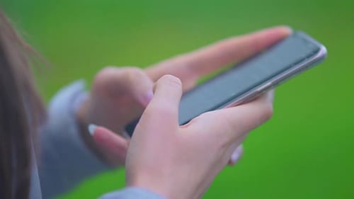 Girl Holding And Typing Text On Smartphone - Woman Using A Touchscreen Cellphone. - close up shot