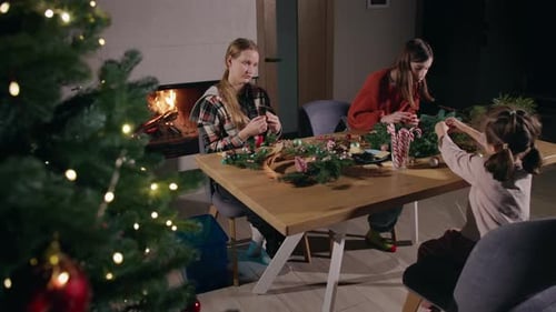 Family Making Christmas Wreath by the Fireplace