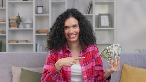 Happy Woman Holds Cash on Sofa