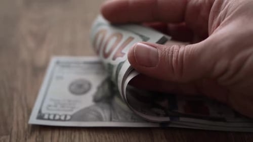 Dollar bills on wooden table close up counting slow motion