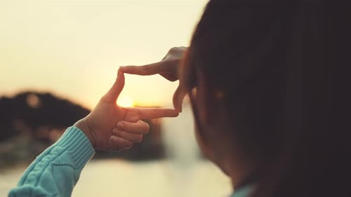 New year planning and vision concept, Close up of woman hands making frame gesture with sunset