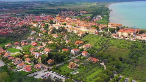 Slow aerial dolly of Italy city on mountain top overlooking a turquoise watered lake.