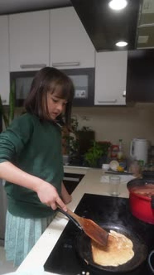 A Young Girl Enthusiastically Cooking Delicious Pancakes in Her Cozy Home Kitchen Space