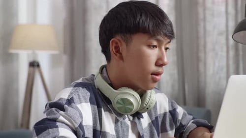 Young Adult Typing on Laptop at Desk
