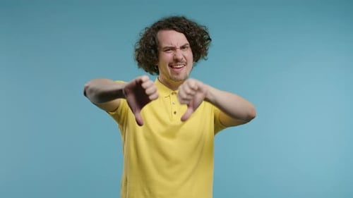 Young Curly Haired Man with Sign of dislikeEuropean Dude Expressing Thumbsdown