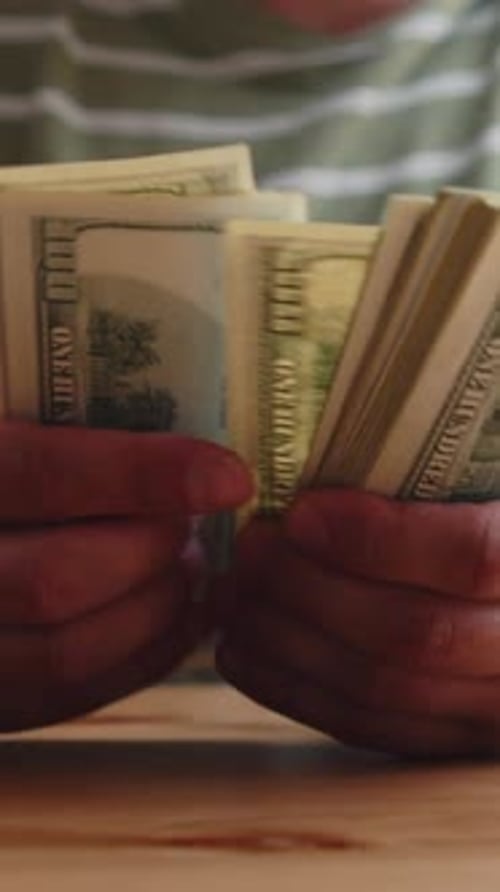 Hands Counting US Dollars At Table In Cozy Living Room Interior Vertical View