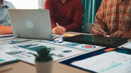 Team Collaboration in Modern Office Workspace with Digital Devices and Data Visu