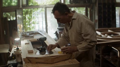 Old Man Carpenter Applies Glue Onto Wooden Door in Workshop