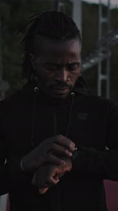 Active African American Man Using Activity Tracker on Smartwatch Before Run Workout Standing on City