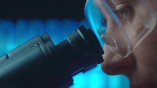 Adult Examines Specimen Through a Powerful Microscope