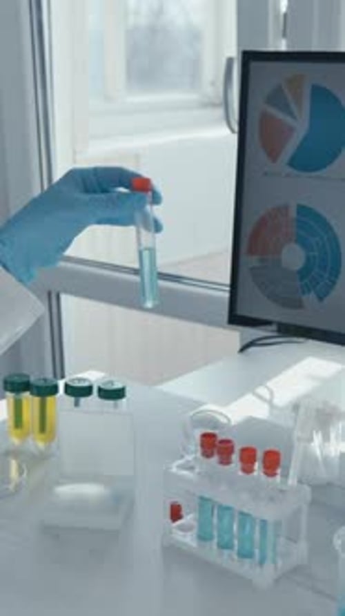 Gloved Hand Holding Test Tube of Blue Liquid