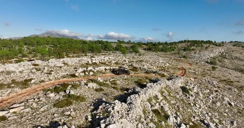 Aerial tracking shot of a buggy driving off-road in the mountains.