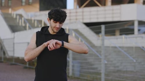 Sportsman Looking at Smartwatch at Modern Street Track