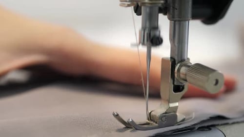 Close Up Slow Video of Woman's Hand Sews Grey Fabric on a Professional Sewing Machine at the
