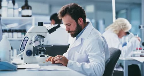 Man and Woman Working with Microscopes in a Lab