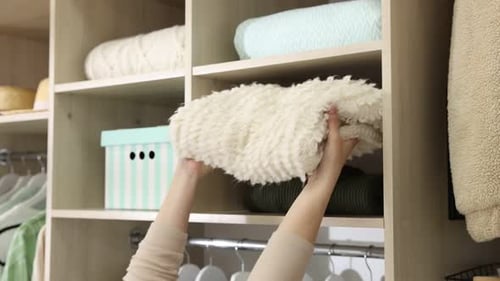 Woman putting plaid on shelf in closet, closeup