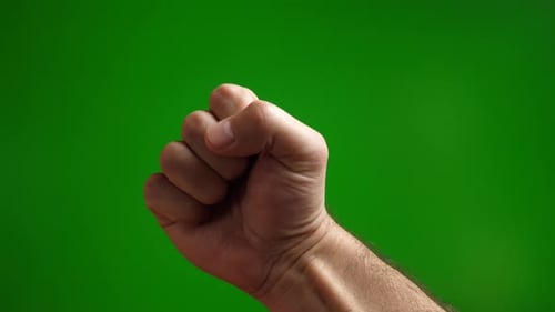 36a. A man makes a threatening fist on a green background.