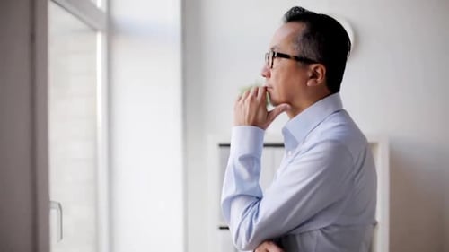 Pensive Asian Businessman at Office Window