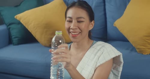 Woman Wipes Face and Drinks Water After Workout