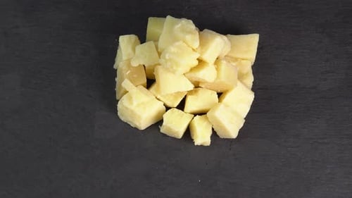 Pieces of parmesan cheese rotate on a black background. Firm aromatic aged cheese. Traditional