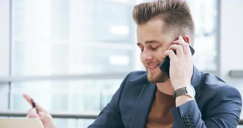 4k video footage of a handsome young businessman making a phonecall while working in his office