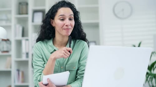 Woman Attending Virtual Meeting and Taking Notes