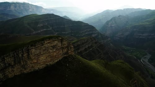 Dramatic Sunlit Mountain Valley Sunlight Pierces Through Clouds Over a Deep Valley with a Winding