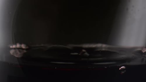 Red wine drops falling into crystal goblet in super slow motion studio shot