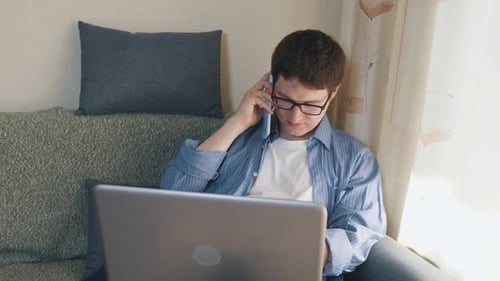 Young Adult Working on Laptop and Talking on Phone