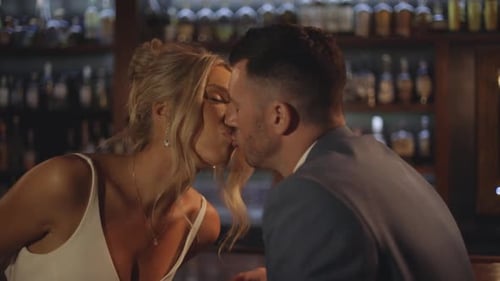 Stylish groom and bride share a romantic kiss in a moody bar,