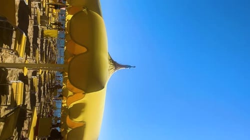 Vertical slow motion shot of yellow umbrella on a beach near by the sea