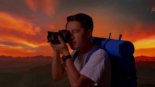 Vue latérale rapprochée d'un homme asiatique utilisant un appareil photo prenant une photo au sommet de la montagne