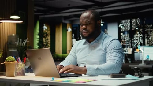 Focused Man Working Late on Laptop in Office