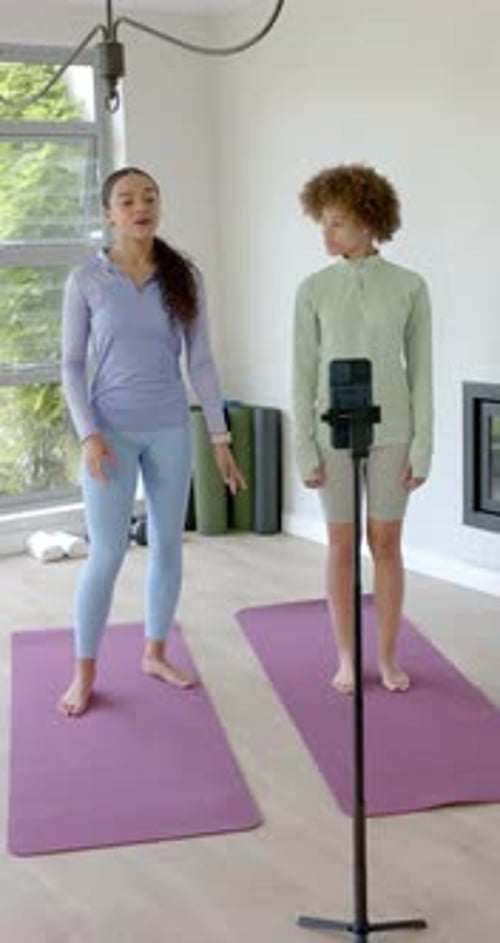 Vídeo vertical: mujeres afroamericanas tocando el reloj mirando al trípode del teléfono filmando un entrenamiento en casa