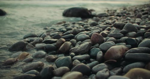 Klare Wellen plätschern vor der steinigen Strandküste mit bunten Felsen. Steigende Flut an der Küste Rocky Erosi