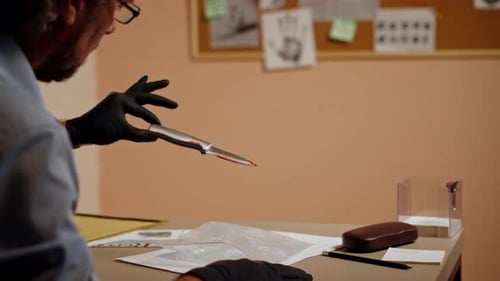 Closeup Detective's Office Middleaged Investigator in Shirt and Tie Sitting Desk Examining Evidence