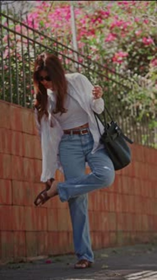 Young Woman Stopping to Adjust Her Shoe on a City Sidewalk
