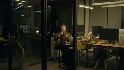 Manager arbeitet nachts im Büro und macht ein Nickerchen mit erhobenen Füßen auf dem Schreibtisch