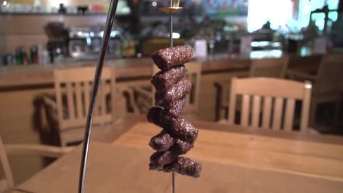 Slow motion shot of cevapcici on a skewer with cream and vegetables in a restaurant