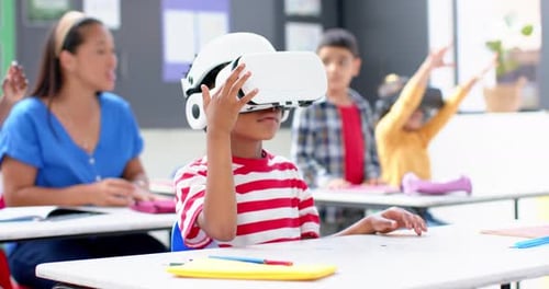 In school, boy using VR headset in classroom with teacher and students
