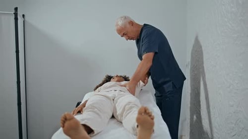 Therapist Doing Manual Treatment in Clinic Ward Grey Hair Osteopath Bending