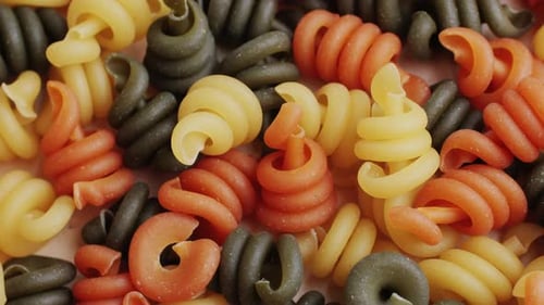 Colorful uncooked pasta spirals close up food background
