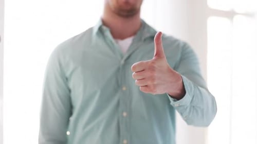 Man Giving Thumbs Up Gesture Indoors During the Day