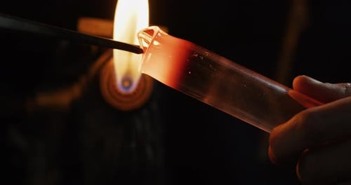 Slow motion macro of glass blower working with flame on a handmade art piece of glass from preciou