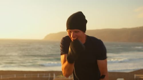 Determined Fighter Hitting By Hands in Air Near Sea at Sunset
