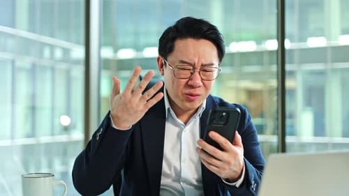 Frustrated Businessman Reacts Angrily to Bad News on Phone in Office