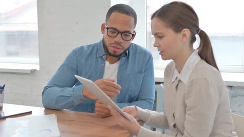 Colleagues Discussing Business on a Tablet in Office