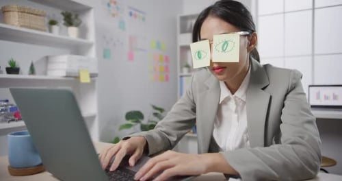 Woman Working at Computer with Eye Drawings on Glasses